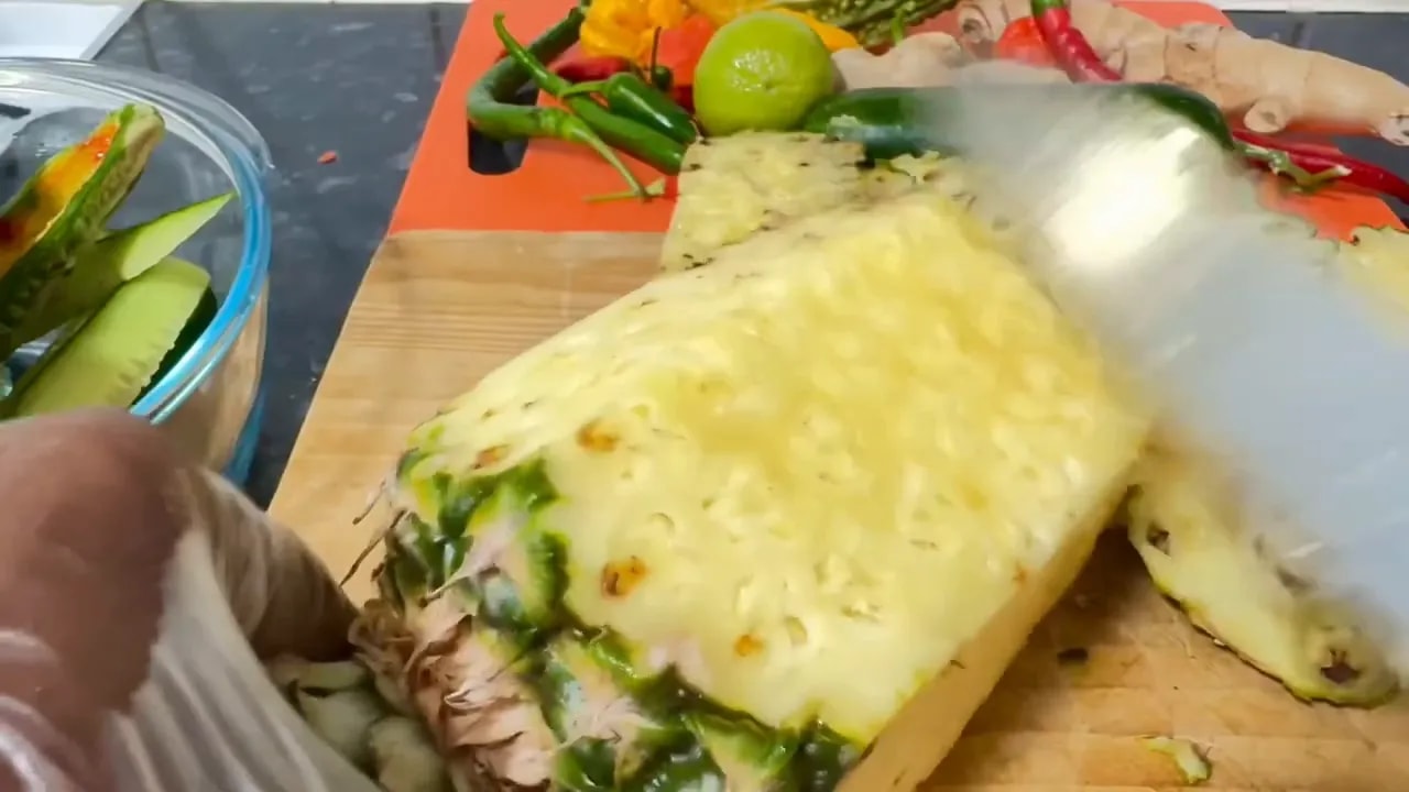 Whole bitter melon on a cutting board with chili peppers, lime, and other fresh ingredients