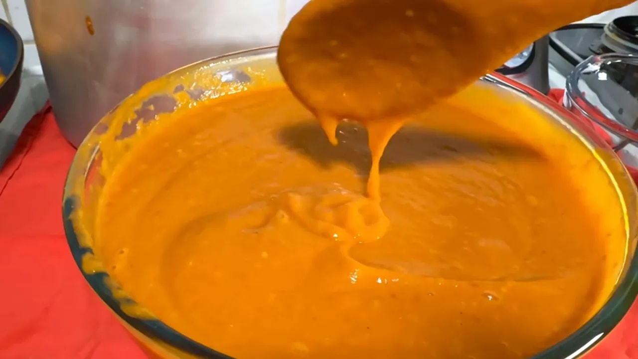 Slow thick pour of Jamaican habanero pepper sauce from a spoon into a pot